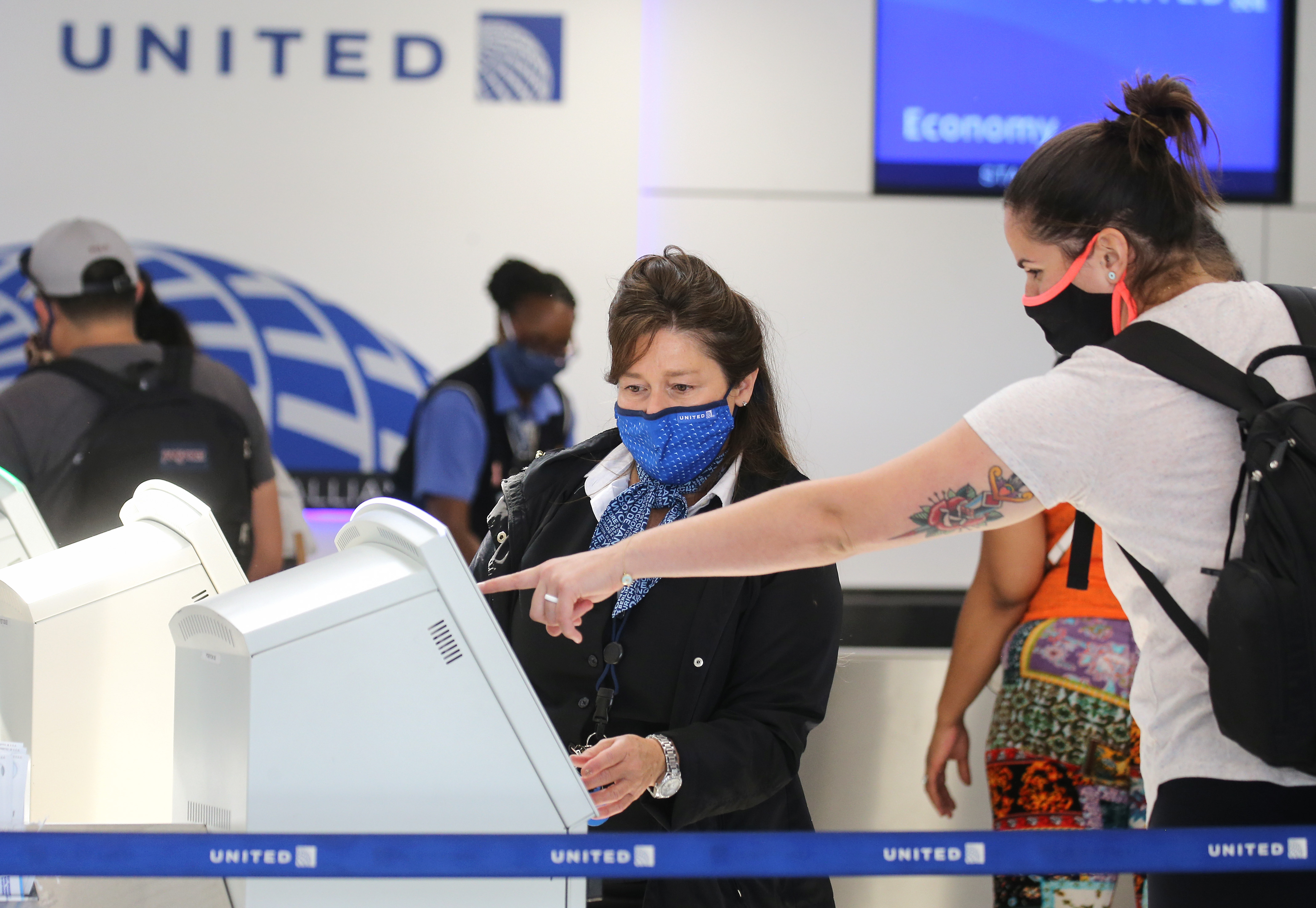 A United Airlines employee wears a required face covering along with a passenger at check-in at Los Angeles International Airport on Oct. 1, 2020 in Los Angeles. (Mario Tama/Getty Images)