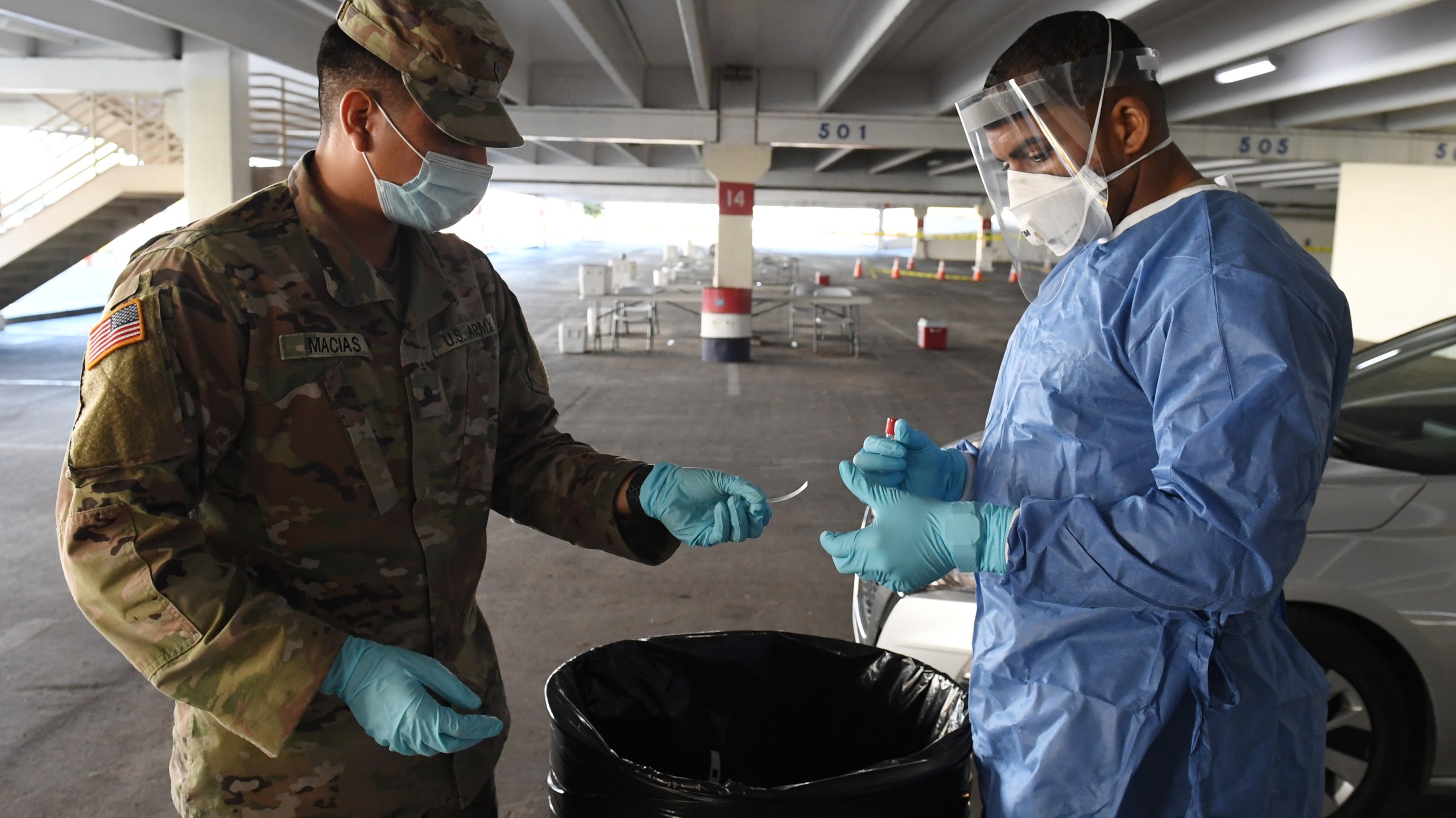 Spc. Jonathan Macias (L) and Spc. Demetrie Barnett of the Nevada National Guard prepare a coronavirus specimen sampling tube after administering a test during a preview of a free drive-thru testing site in the parking garage of the Texas Station Gambling Hall & Hotel on Nov. 12, 2020 in North Las Vegas, Nevada. (Ethan Miller/Getty Images)