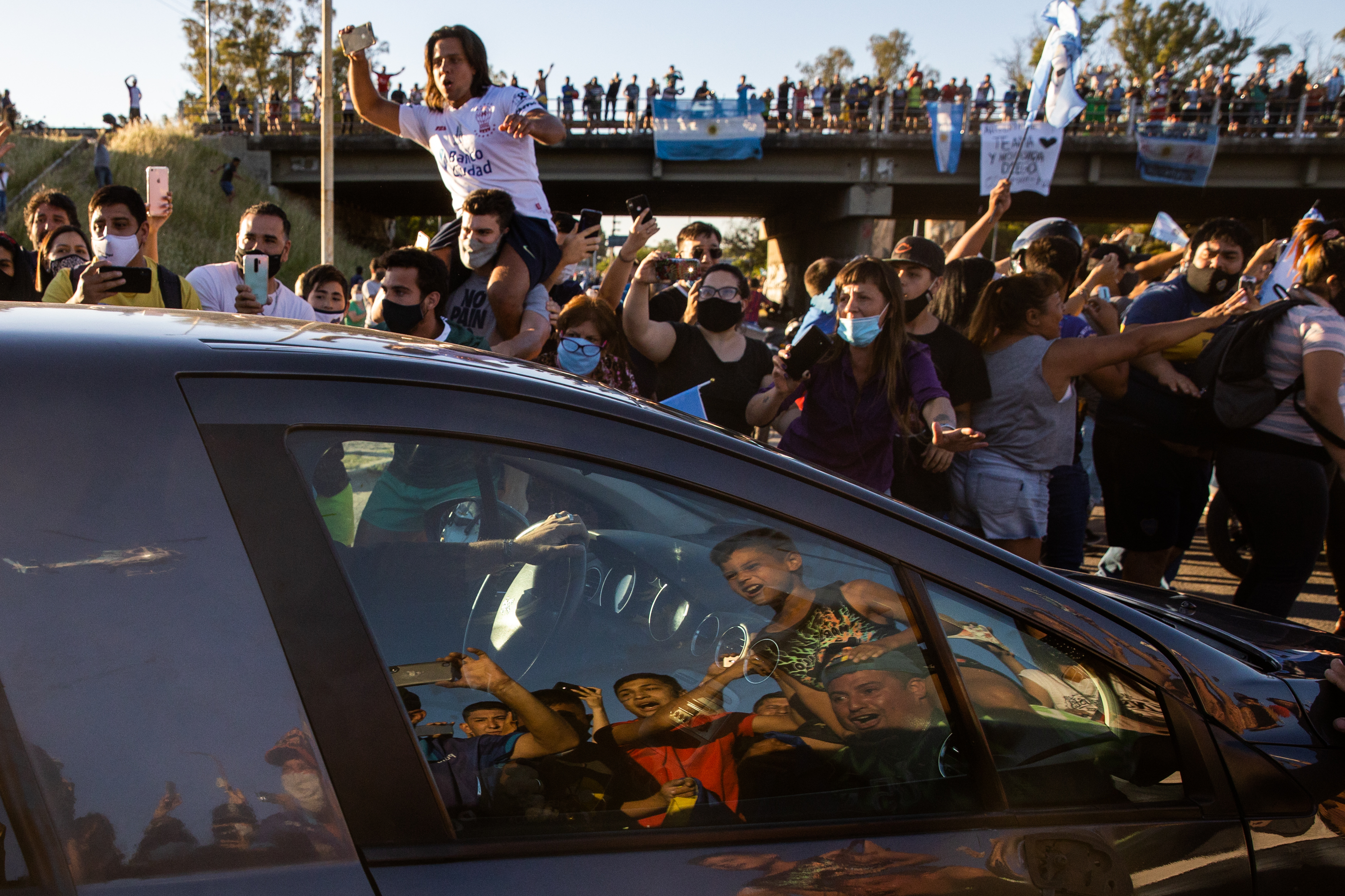 Fans on the side of the highway cheer for the hearse carrying the body of Diego Maradona that transports him through 25 de Mayo Highway to Jardín de Bella Vista before the burial ceremony on Nov. 26, 2020. (Tomas Cuesta / Getty Images)