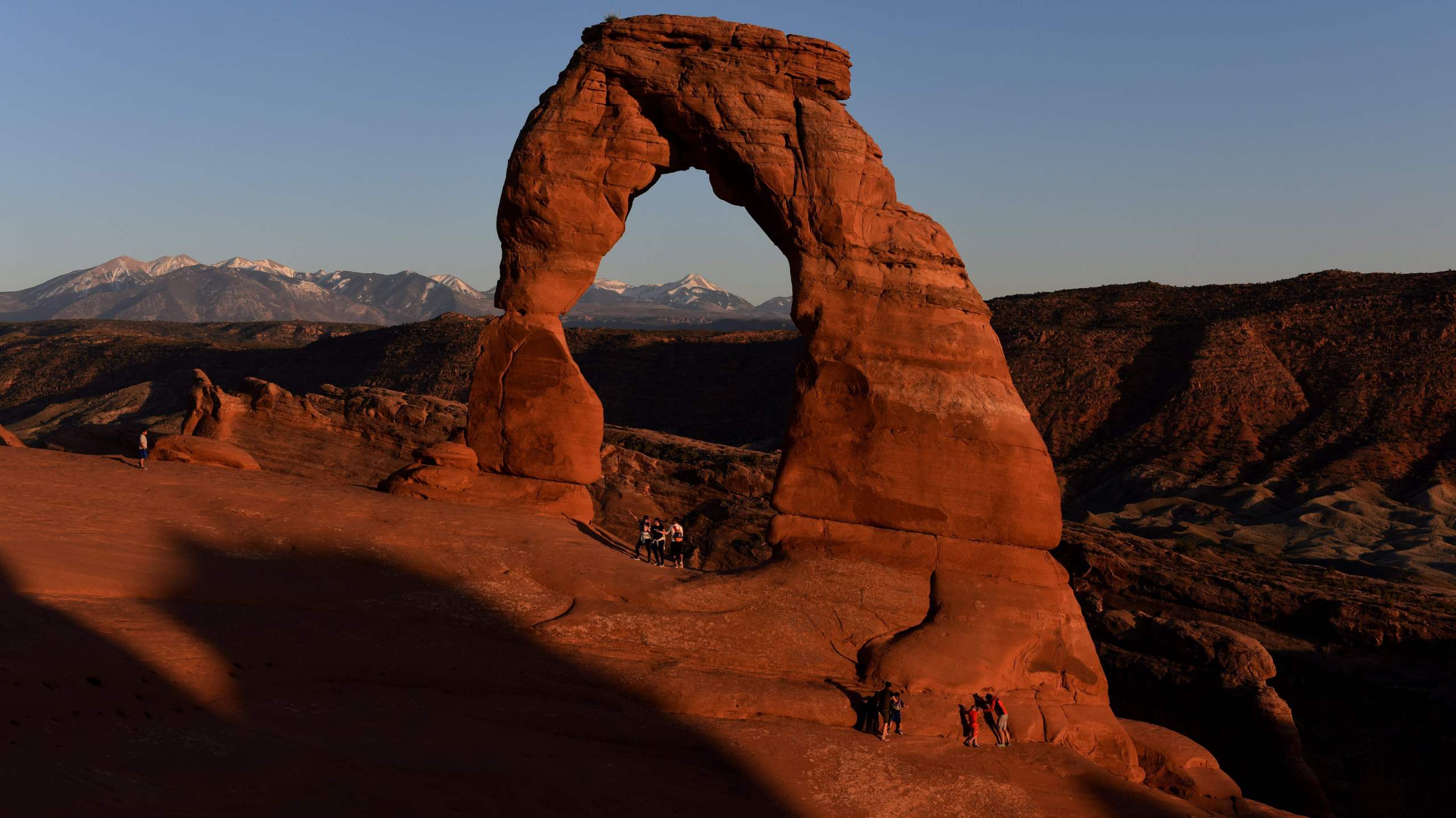 Hikers walk beside the Delicate Arch at sunset in the Arches National Park near Moab, Utah on April 21, 2018. - The park which has over 2000 arches that were formed over 100 million years by a combination of water, ice, extreme temperatures and underground salt movement. (Photo by Mark Ralston / AFP) (Photo credit should read MARK RALSTON/AFP via Getty Images)