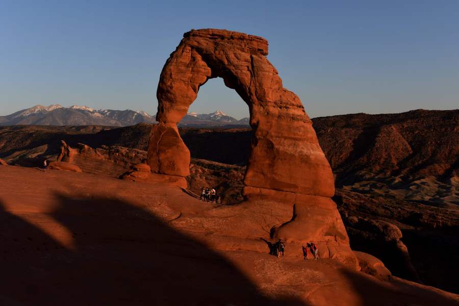 Hikers walk beside the Delicate Arch at sunset in the Arches National Park near Moab, Utah on April 21, 2018. - The park which has over 2000 arches that were formed over 100 million years by a combination of water, ice, extreme temperatures and underground salt movement. (Photo by Mark Ralston / AFP) (Photo credit should read MARK RALSTON/AFP via Getty Images)