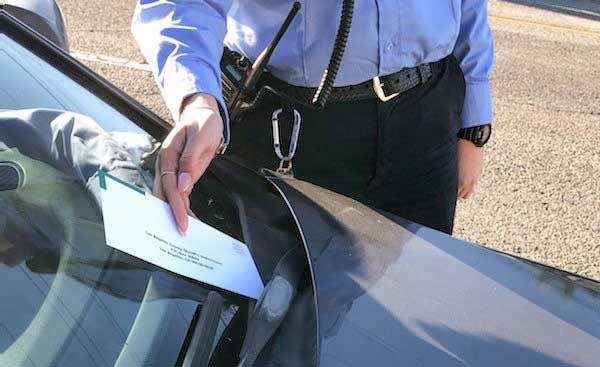 An officer is seen placing a parking citation on a car in this undated photo released by the Los Angeles County Sheriff’s Department.