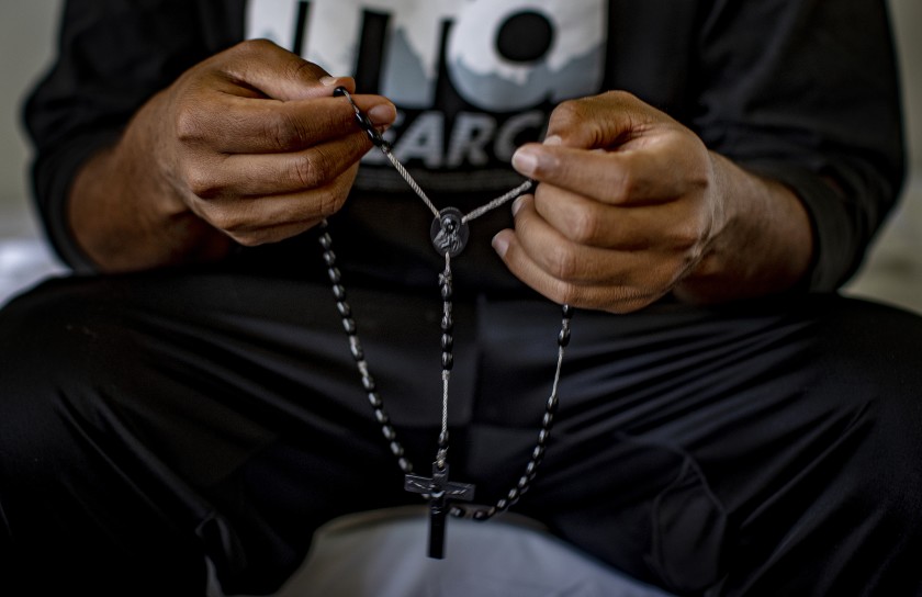 Tsegai, who fled persecution in Eritrea, holds a rosary given to him by family members. After he was released from the Adelanto ICE Processing Facility on Sept. 8, 2020, an Episcopal church in San Bernardino County took him in. Shut down by the COVID-19 pandemic, some churches are housing immigrants released from detention. (Gina Ferazzi / Los Angeles Times)