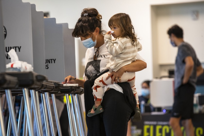 Billie Montague, 2, puts an “I voted” sticker on her nose while for waiting for her mother, Ashley Montague, to finish voting at Marina Park Community Center in Newport Beach on Nov 3, 2020. (Allen J. Schaben / Los Angeles Times)