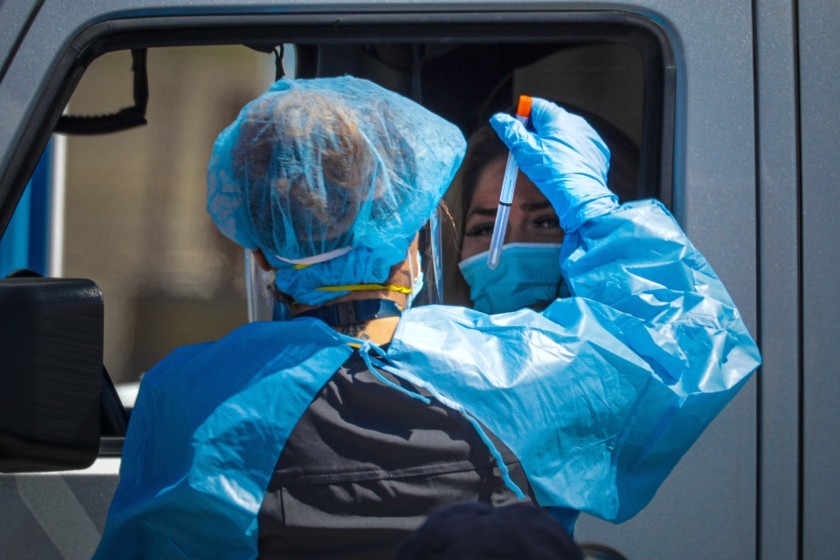 A San Bernardino County health care worker collects a sample at a drive-through coronavirus testing site in Victorville in 2020. (Irfan Khan / Los Angeles Times)