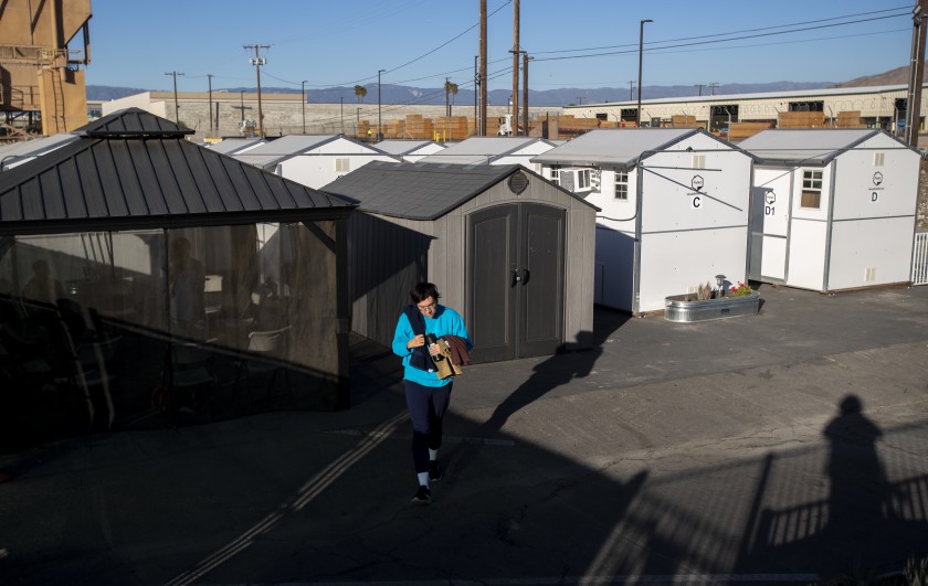 A resident of a "tiny home" village in Riverside walks to the common shower area in November 2020. (Gina Ferazzi / Los Angeles Times)