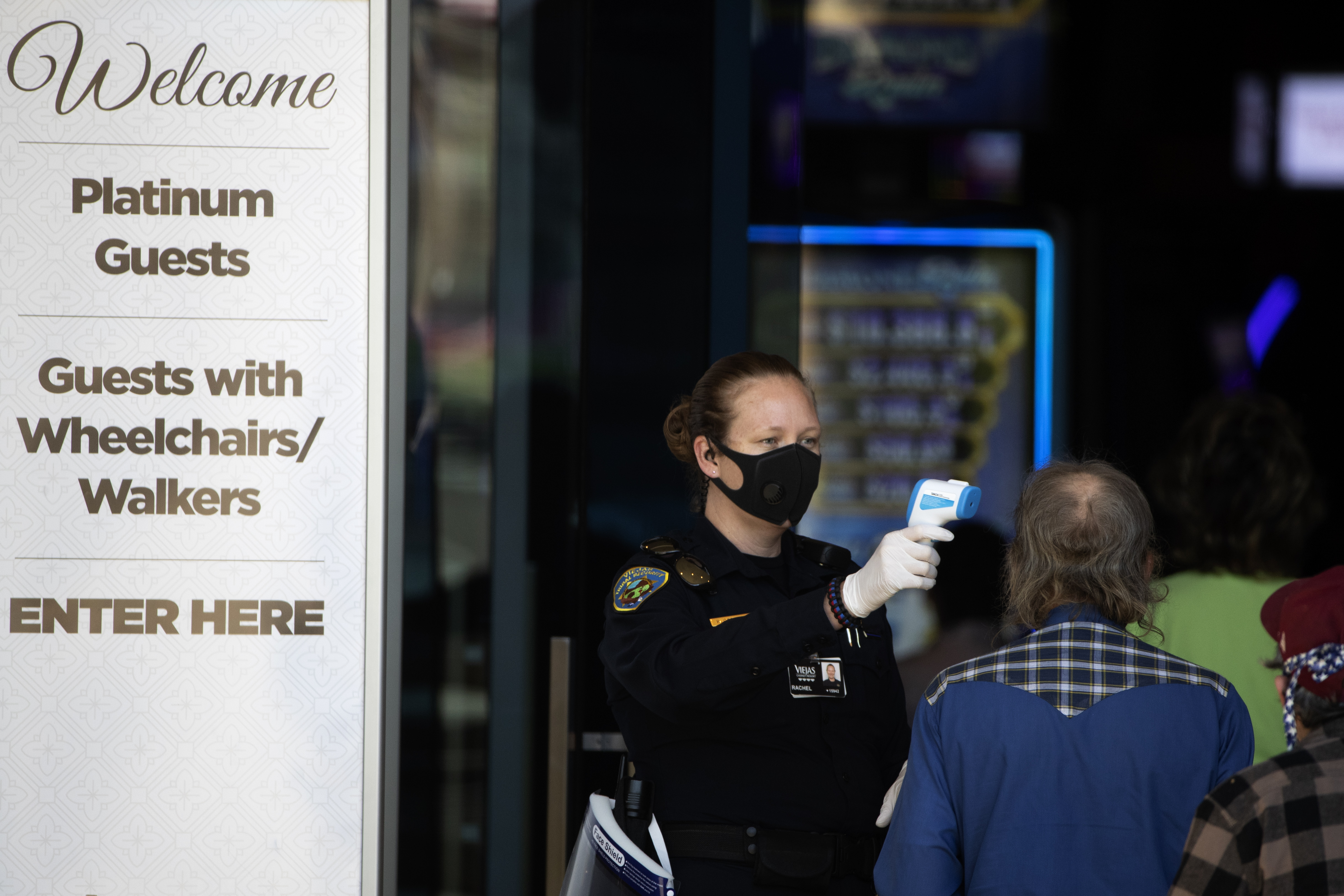 A security official checks the temperature of a man at the entrance to the Viejas Casino and Resort in Alpine, San Diego County, as it reopens on May 18, 2020. (Gregory Bull / Associated Press)