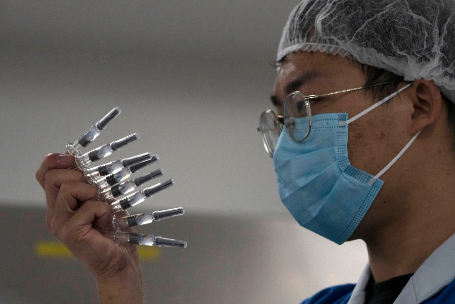 In this Sept. 24, 2020, file photo, an employee manually inspects syringes of the SARS CoV-2 Vaccine for COVID-19 produced by Sinovac at its factory in Beijing. (Ng Han Guan/AP Photo)