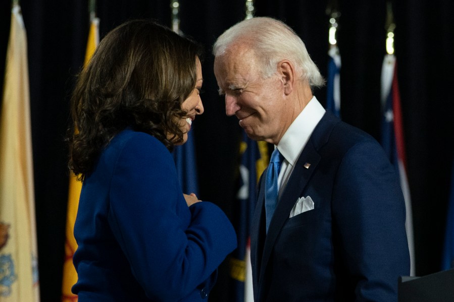 In this Aug. 12, 2020, file photo, Democratic presidential candidate former Vice President Joe Biden and his running mate Sen. Kamala Harris pass each other as Harris moves to the podium to speak during a campaign event at Alexis Dupont High School in Wilmington, Del. (Carolyn Kaster / Associated Press)