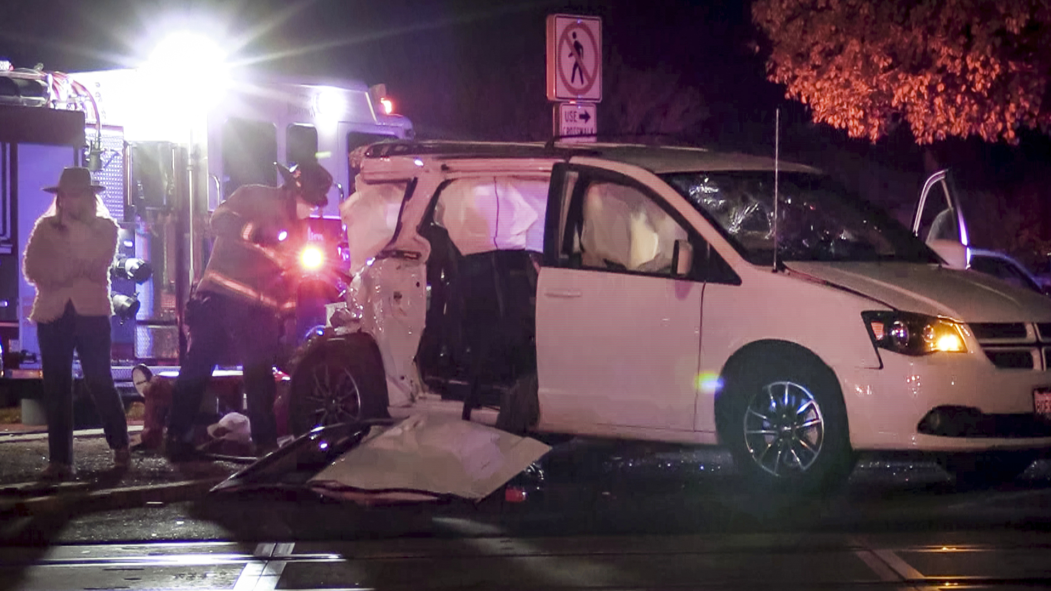 In this image from video, a firefighter inspects the scene where a small child was killed when a minivan was struck by a train while a family was waiting to enter a drive-thru Christmas lights display in Fresno, Calif., on Tuesday, Dec. 1, 2020. Police say the van with four people inside was stopped at an intersection when it was hit by an Amtrak train. (Craig Kohlruss/The Fresno Bee via AP)