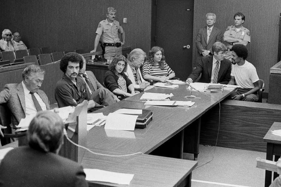 In this Aug. 22, 1983, file photo, four persons charged in connection with the June 2, 1983, fatal shooting of Los Angeles Police Officer Paul Verna sit with their attorneys during a preliminary hearing in a San Fernando, Calif., courtroom. Seated second from left to right, Kenneth Gay, an unidentified attorney, Robin Gay, attorney Elmer Docken, Pam Cummings, attorney Edward Rucker and Reynard Cummings. (AP Photo/Michael Tweed, File)