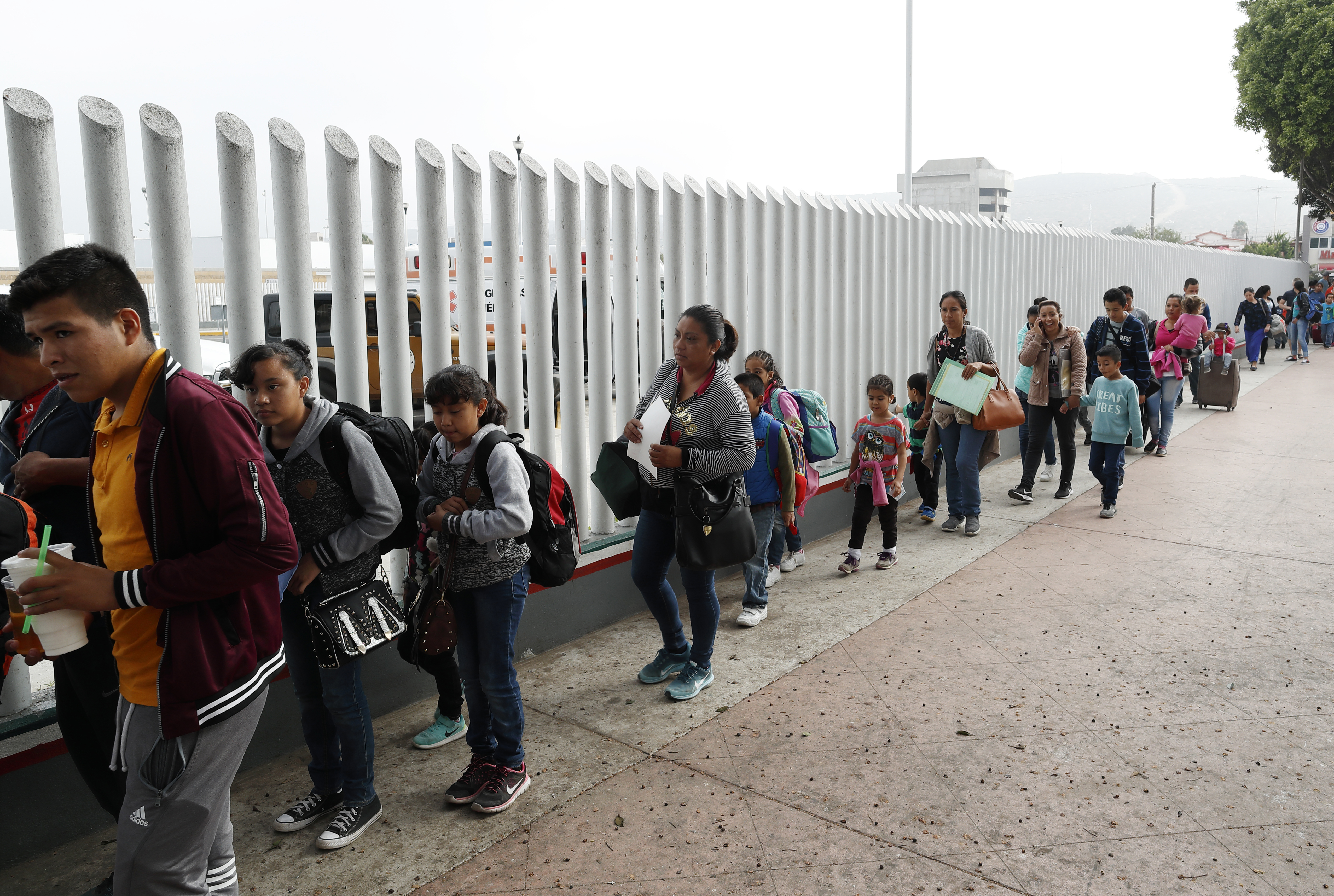 This July 26, 2018, file photo shows people lining up to cross into the United States to begin the process of applying for asylum near the San Ysidro port of entry in Tijuana, Mexico. (Gregory Bull / Associated Press)