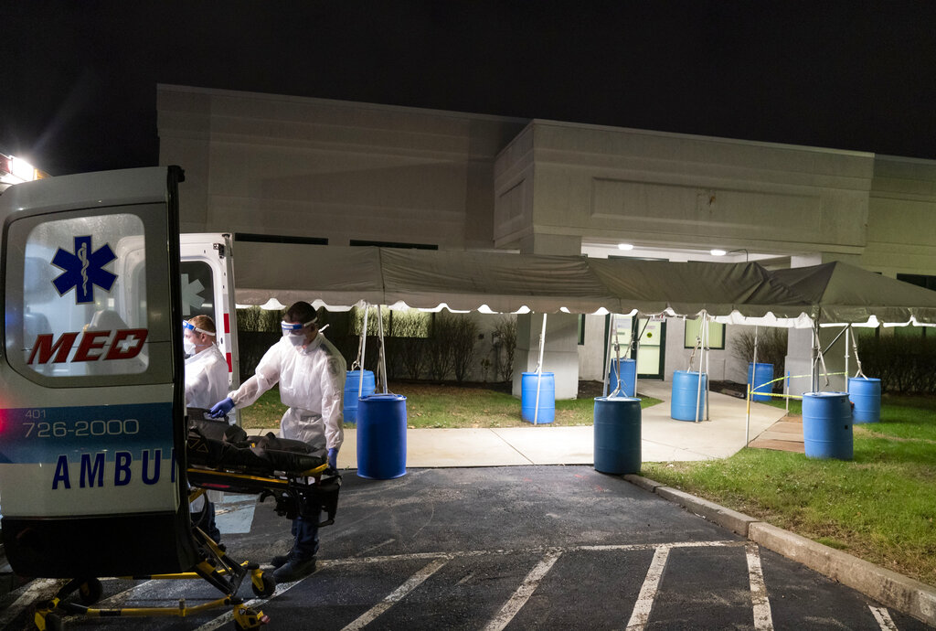 In this Dec. 1, 2020, file photo, a stretcher is loaded back into an ambulance after EMTs dropped off a patient at a newly opened field hospital operated by Care New England to handle a surge of COVID-19 patients in Cranston, R.I. (AP Photo/David Goldman)