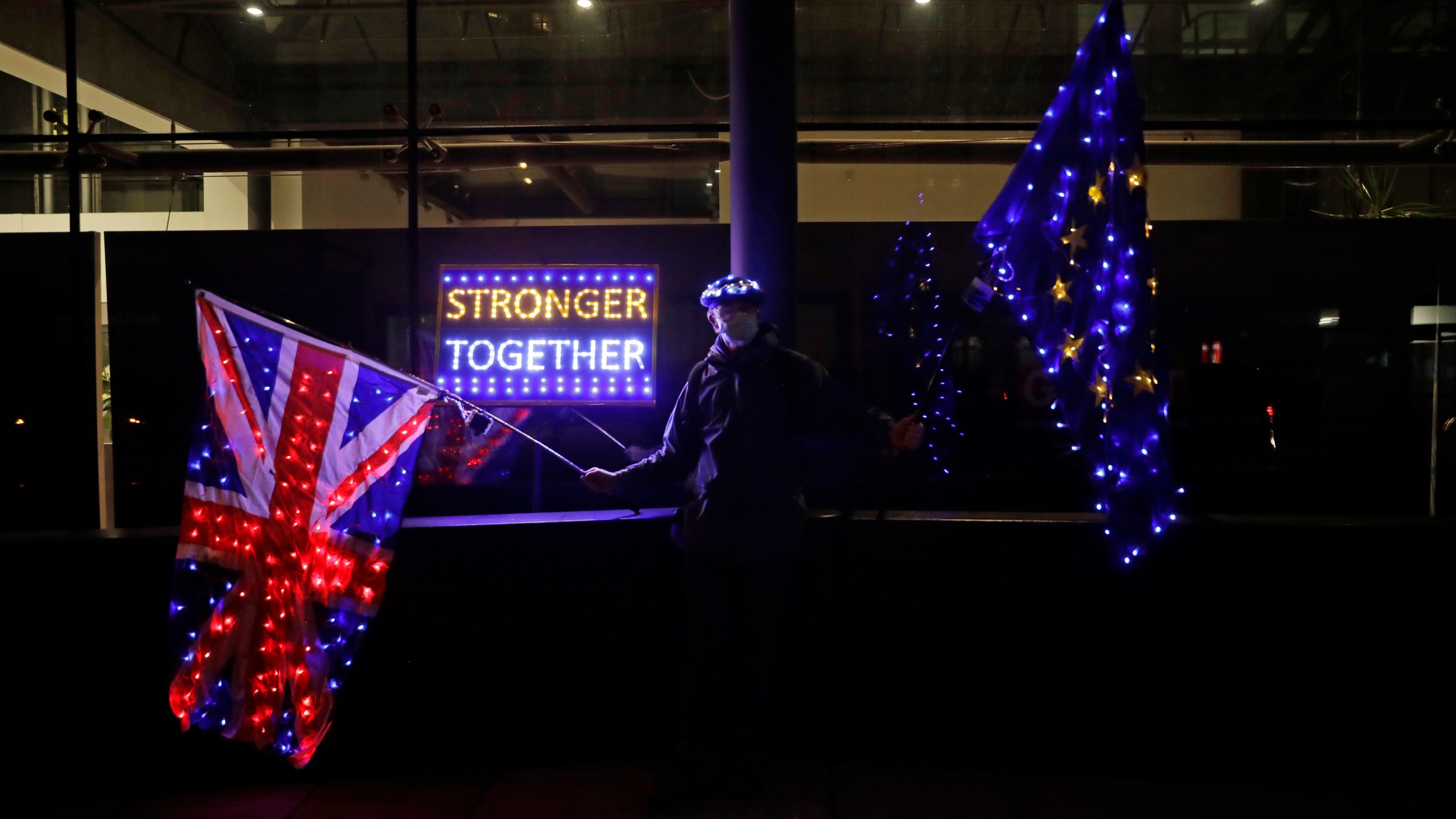 A pro-European Union membership supporter protests with illuminated European and Union flags outside Brexit trade negotiations between Britain and the EU at the Conference Centre in London, Friday, Dec. 4, 2020. (Matt Dunham/AP Photo)