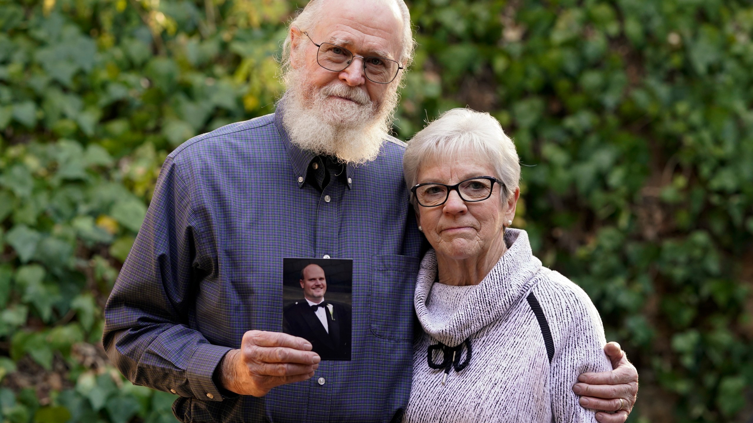 Clark McIlvain and Kathleen McIlvain hold a photo of their son, Charles McIlvain, at their home in Woodland Hills on Dec. 3, 2020. (Ashley Landis / Associated Press)