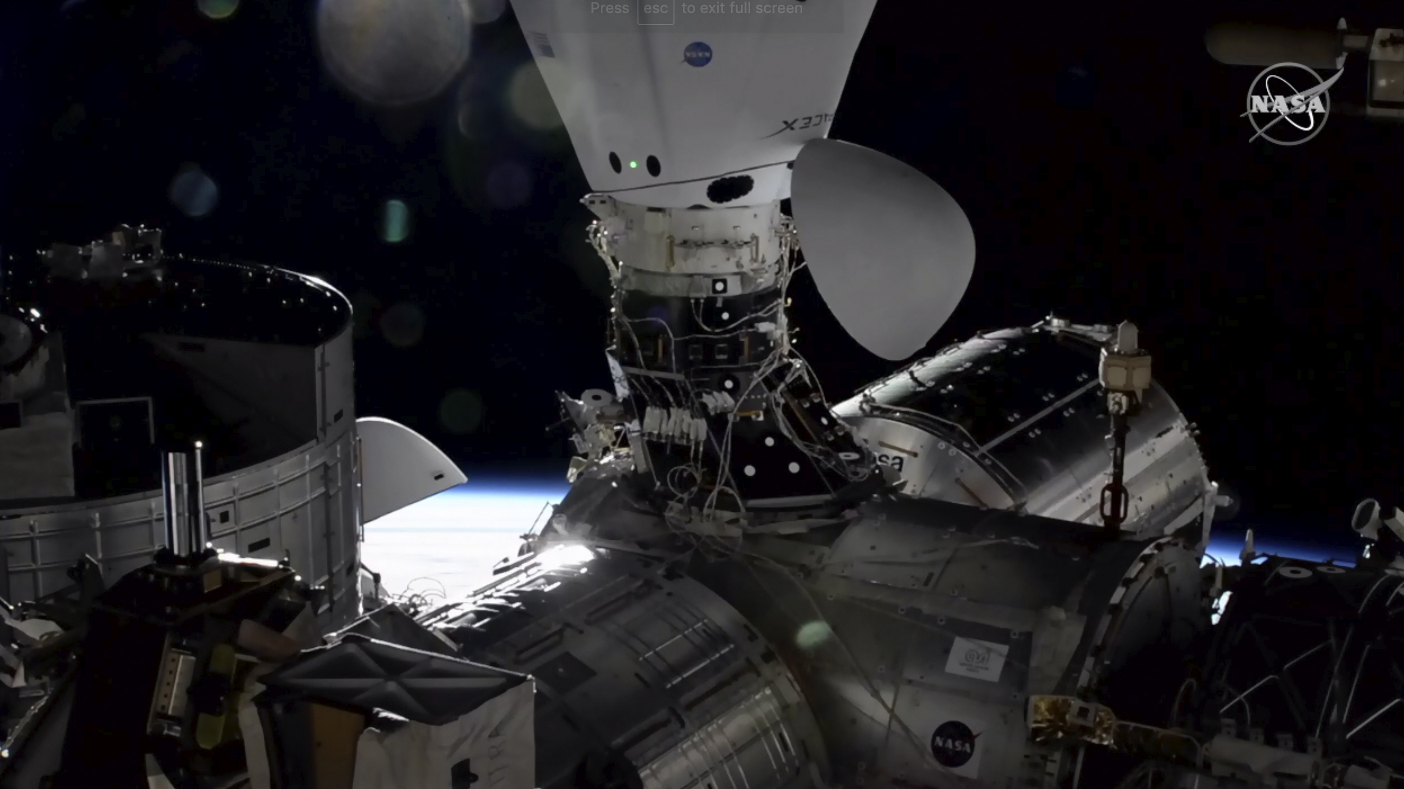 In this image taken from NASA TV the Dragon cargo capsule docks at the International Space Station, Monday, Dec. 7, 2020, alongside a Dragon crew capsule that carried up astronauts three weeks ago. (NASA via AP)