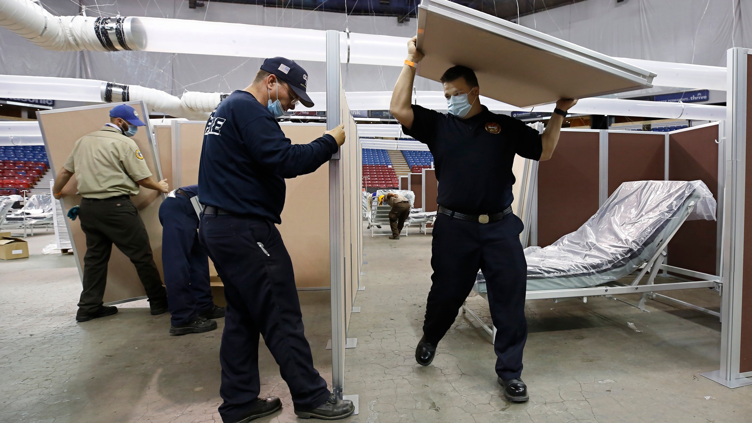 In this April 18, 2020, file photo, partitions are installed between beds as Sleep Train Arena is turned into a 400-bed emergency field hospital to help deal with the coronavirus, in Sacramento, Calif. Due to the recent spike in COVID-19 cases officials are rushing to reopen the former home of the NBA's Sacramento Kings, to patients. (AP Photo/Rich Pedroncelli, File)