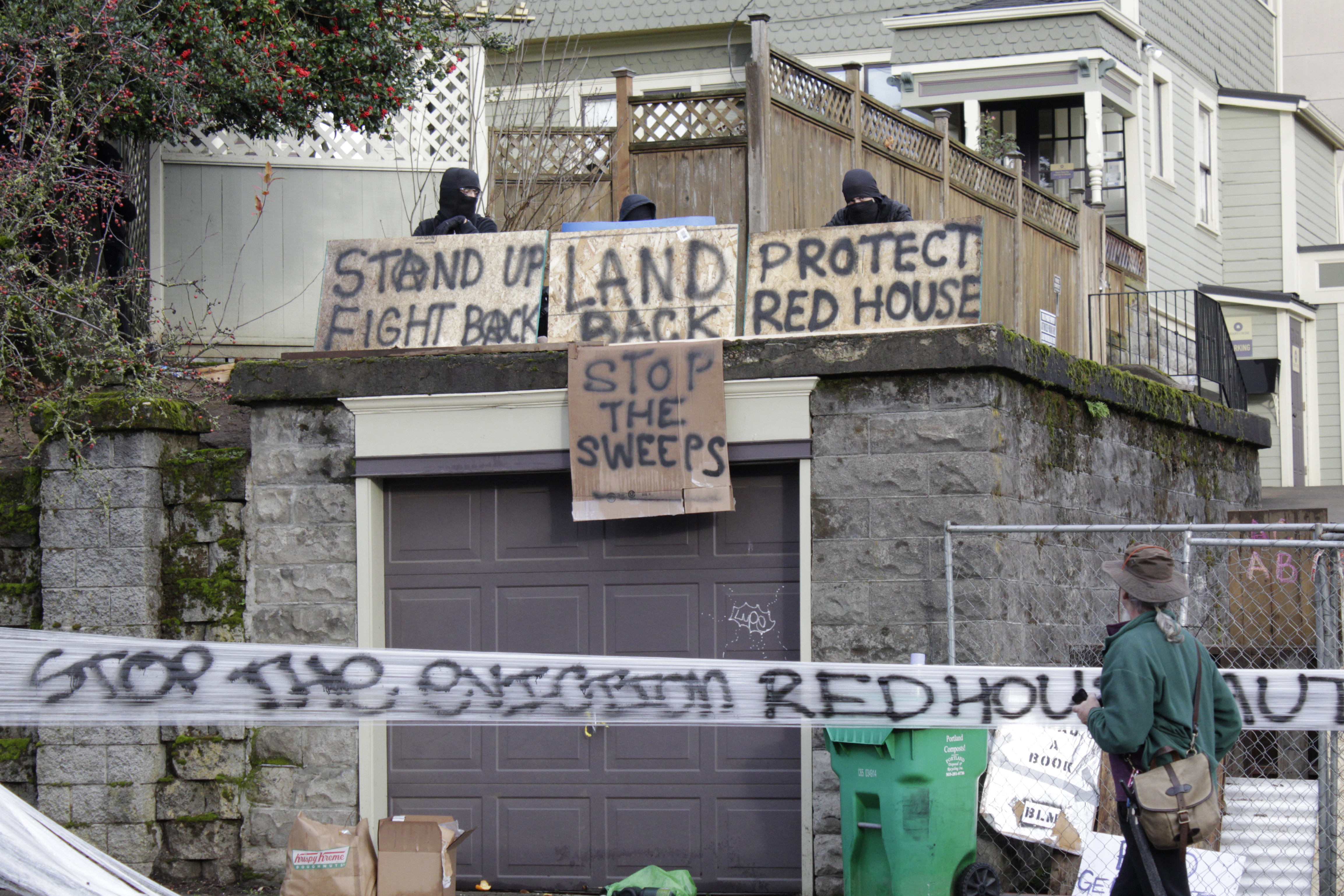 Masked protesters by an occupied home speak with a neighborhood resident opposed to their encampment and demonstration in Portland, Ore., on Dec. 9, 2020. (Gillian Flaccus / Associated Press)