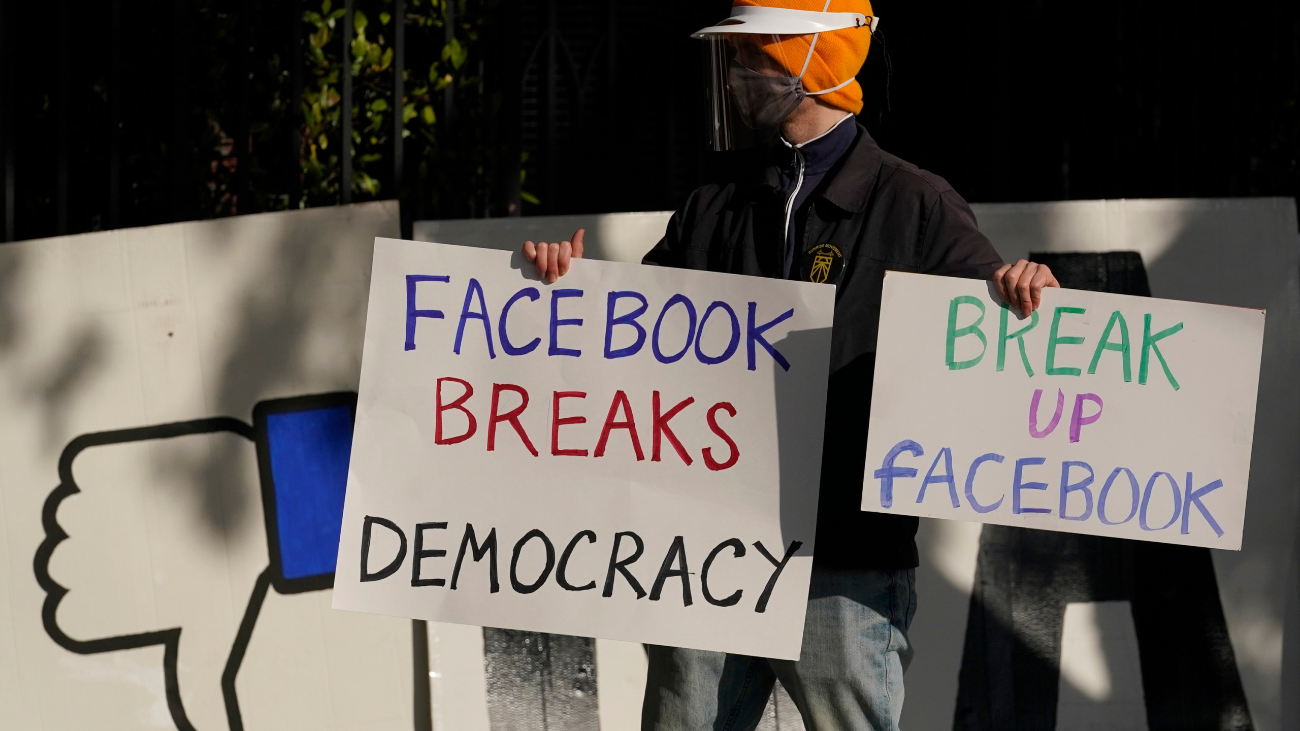 In this Saturday, Nov. 21, 2020, file photo, a demonstrator joins others outside of the home of Facebook CEO Mark Zuckerberg to protest what they say is Facebook spreading disinformation in San Francisco. Federal regulators asked Wednesday, Dec. 9, 2020, for Facebook to be ordered to divest its Instagram and WhatsApp messaging services as the U.S. government and 48 states and districts accused the company of abusing its market power in social networking to crush smaller competitors. The antitrust lawsuits were announced by the Federal Trade Commission and New York Attorney General Letitia James. (AP Photo/Jeff Chiu, File)