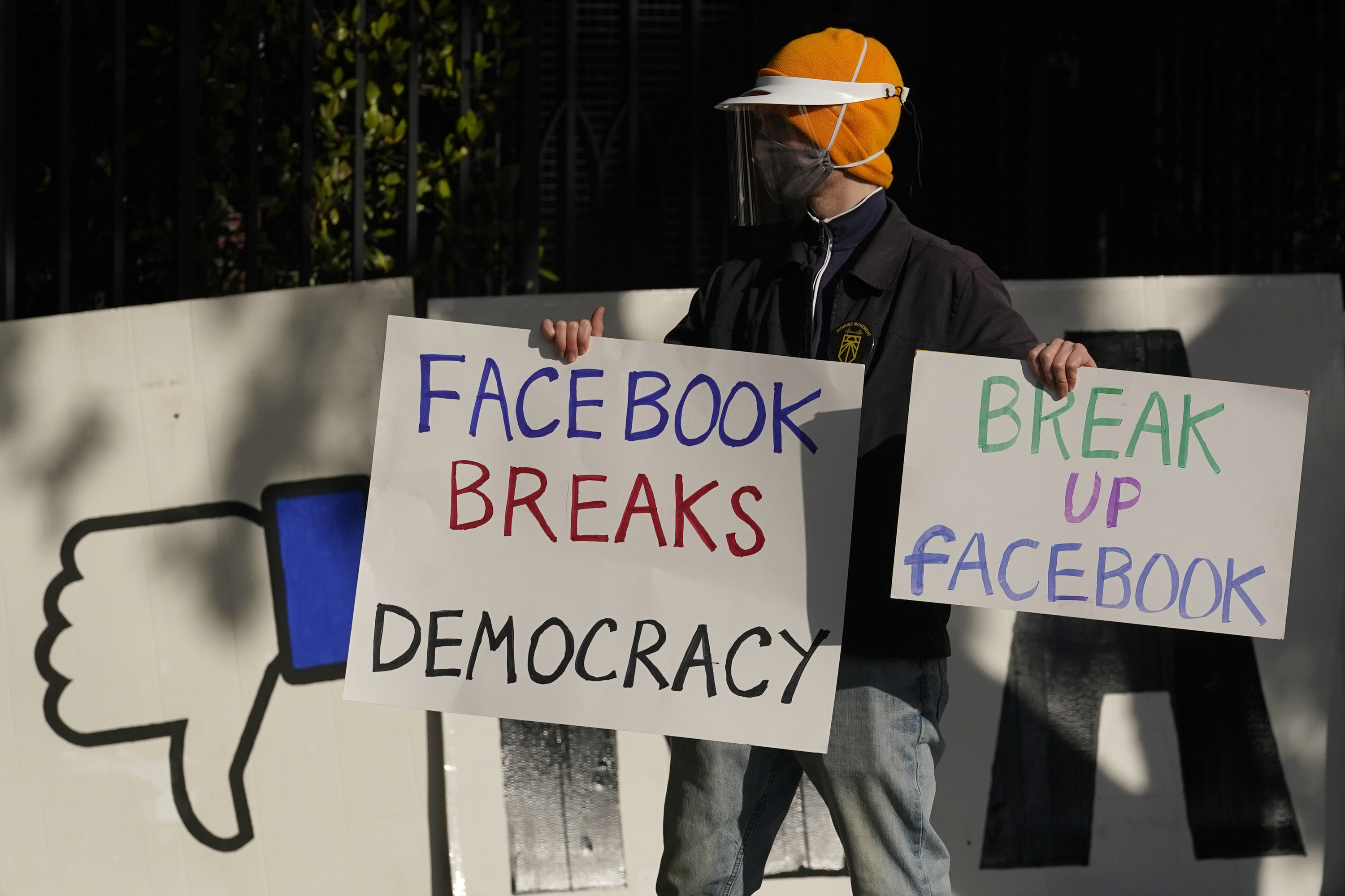 In this Saturday, Nov. 21, 2020, file photo, a demonstrator joins others outside of the home of Facebook CEO Mark Zuckerberg to protest what they say is Facebook spreading disinformation in San Francisco. Federal regulators asked Wednesday, Dec. 9, 2020, for Facebook to be ordered to divest its Instagram and WhatsApp messaging services as the U.S. government and 48 states and districts accused the company of abusing its market power in social networking to crush smaller competitors. The antitrust lawsuits were announced by the Federal Trade Commission and New York Attorney General Letitia James. (AP Photo/Jeff Chiu, File)