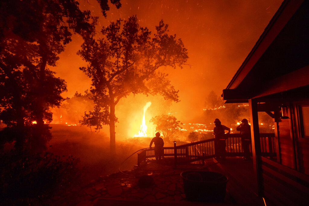 In this Aug. 21, 2020, file photo, firefighters watch flames from the LNU Lightning Complex fires approach a home in the Berryessa Estates neighborhood of unincorporated Napa County, Calif. (AP Photo/Noah Berger, File)