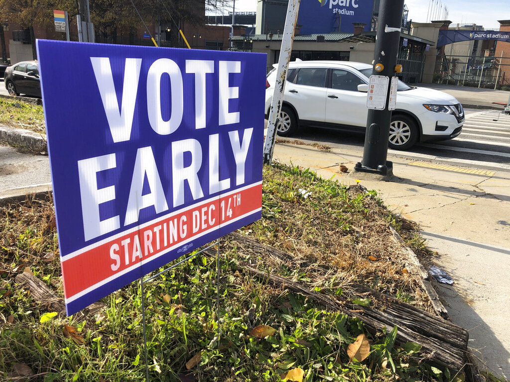 A sign in an Atlanta neighborhood on Friday, Dec. 11, 2020, urges people to vote early in Georgia's two U.S. Senate races. (AP Photo/Jeff Amy)