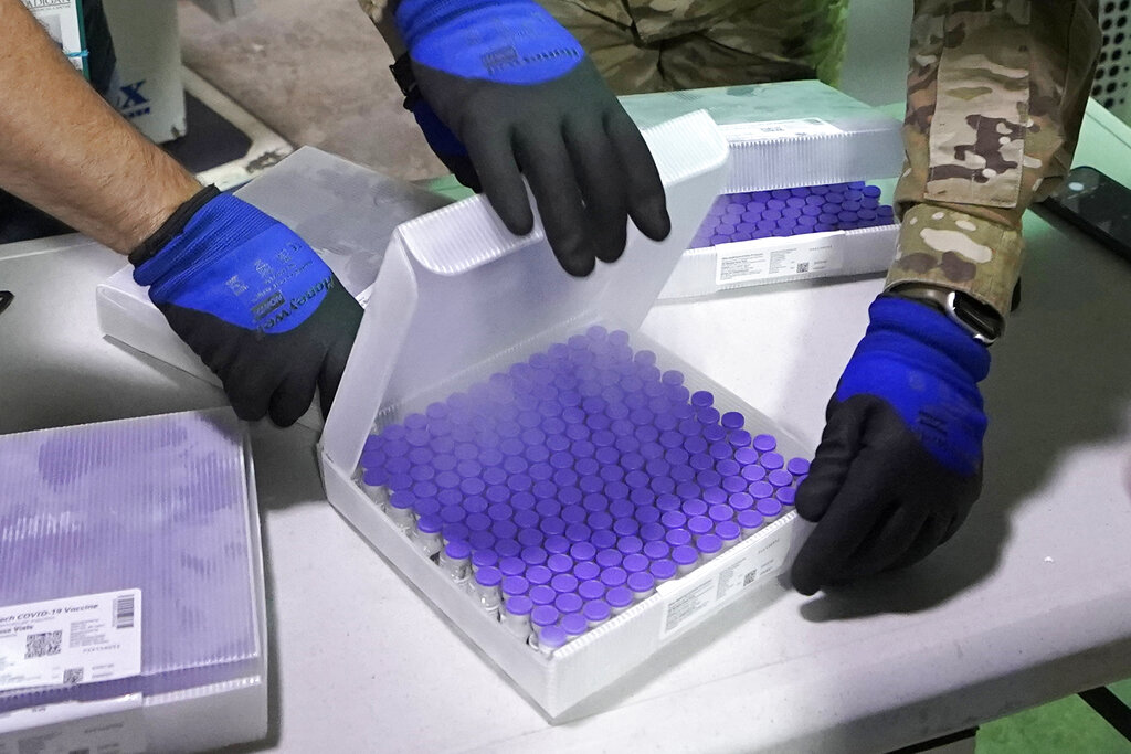 Materials handlers make a quick check of a box of vials of the first shipment of the Pfizer vaccine for COVID-19 before putting it in a freezer on Dec. 15, 2020, shortly after it arrived at Madigan Army Medical Center at Joint Base Lewis-McChord in Washington state, south of Seattle. (AP Photo/Ted S. Warren)