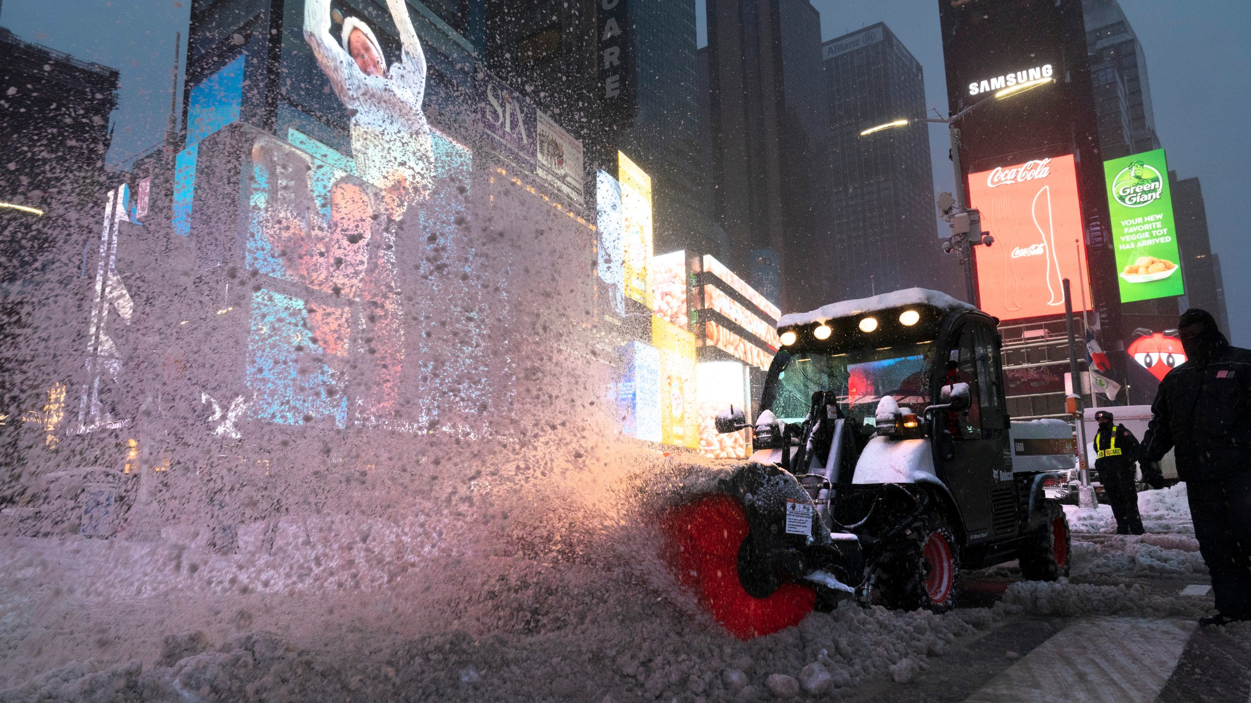 A tractor with a power brush clears snow in New York's Times Square on Dec. 17, 2020. (Mark Lennihan / Associated Press)