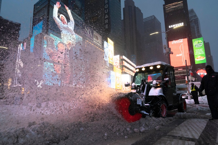 A tractor with a power brush clears snow in New York's Times Square on Dec. 17, 2020. (Mark Lennihan / Associated Press)