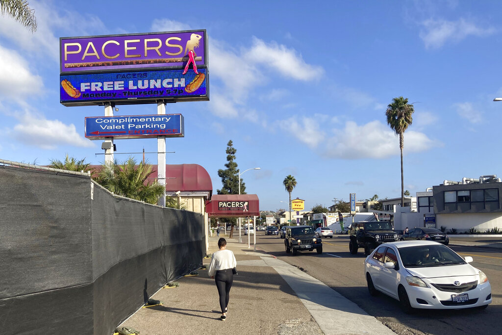 In this Dec. 10, 2020, file photo, a person walks past Pacers Showgirls International in San Diego. San Diego County has suspended enforcement of COVID-19 restrictions on restaurants and live entertainment establishments after a local judge found in favor of two strip clubs that defied a state shutdown order and indicated the ruling applied more broadly. (AP Photo/Elliot Spagat, File)