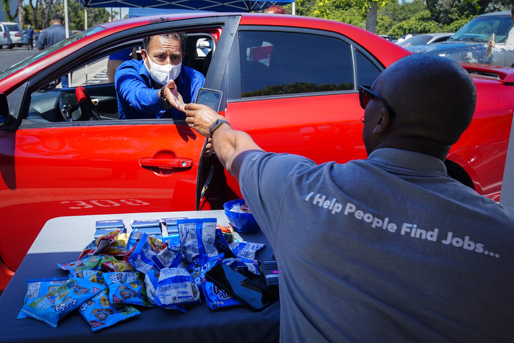 In this May 6, 2020, file photo, Brandon Earl, right, helps David Lenus, a job seeker, fill out an application at a drive up job fair for Allied Universal during the coronavirus pandemic, in Gardena. (AP Photo/Chris Carlson, File)