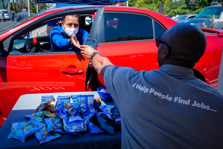 In this May 6, 2020, file photo, Brandon Earl, right, helps David Lenus, a job seeker, fill out an application at a drive up job fair for Allied Universal during the coronavirus pandemic, in Gardena. (AP Photo/Chris Carlson, File)