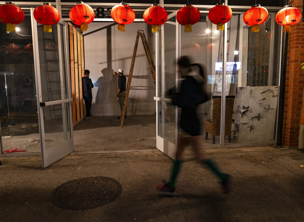 A runner jogs past a former Chinese restaurant being converted into an artist space in the Chinatown district of Los Angeles, Thursday, Dec. 17, 2020. (AP Photo/Damian Dovarganes)