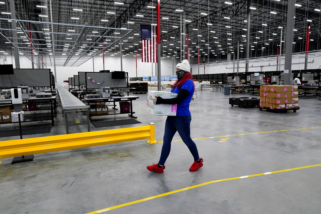 A worker carries a box containing the Moderna COVID-19 vaccine as it is prepared to be shipped at the McKesson distribution center in Olive Branch, Miss., Sunday, Dec. 20, 2020. (AP Photo/Paul Sancya, Pool)