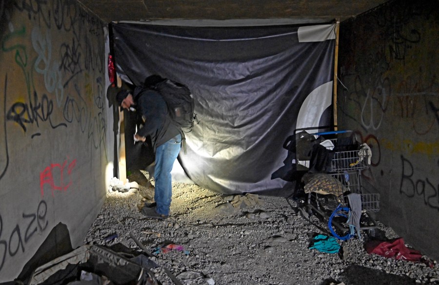 In this Dec. 5, 2020, file photo, Paul Vautrinot of Shine a Light passes though personal belongs as he provides outreach in the underground tunnels to offer counseling, food and water to the homeless living beneath the city in Las Vegas. (David Becker/AP Photo)