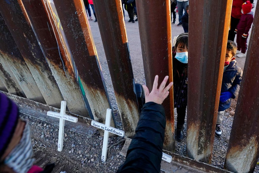 Vicky Chaidez waves to children on the Mexico side of the border fence at the start of a Las Posadas event with several asylum seeking families at the U.S.-Mexico border wall, on Dec. 15, 2020, in Douglas, Ariz. (AP Photo/Ross D. Franklin)