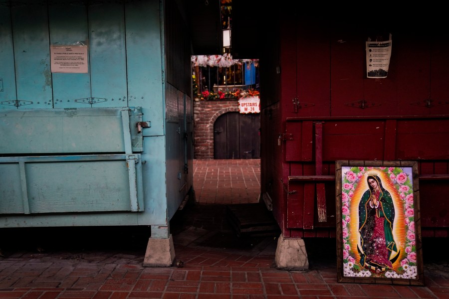 A framed painting depicting Our Lady of Guadalupe is propped against a shuttered market stall on empty Olvera Street in downtown Los Angeles, Wednesday, Dec. 16, 2020. Olvera Street, known as the birthplace of Los Angeles, has been particularly hard hit by the coronavirus pandemic, with shops and restaurants closed and others barely hanging on. (Jae C. Hong / Associated Press)