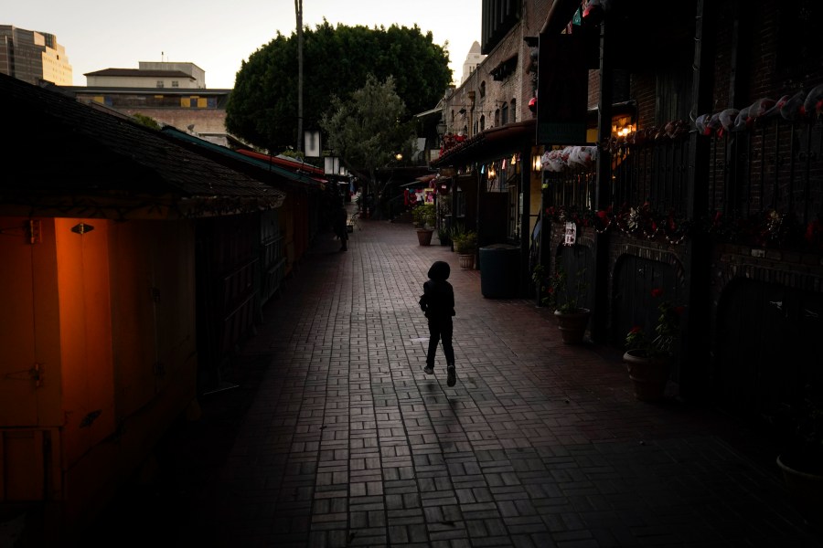 A boy chases a bird on an empty Olvera Street in downtown Los Angeles, Tuesday, Dec. 15, 2020. The tree-covered brick alley typically teeming with tourists is empty. Many of the shops that sell everything from traditional Mexican folk dresses to paintings of artist Frida Kahlo to sombreros are padlocked and the ones open have few, if any, customers. The strains of mariachi trios have fallen silent and the fragrance of taquitos frying has become less pungent. (Jae C. Hong / Associated Press)