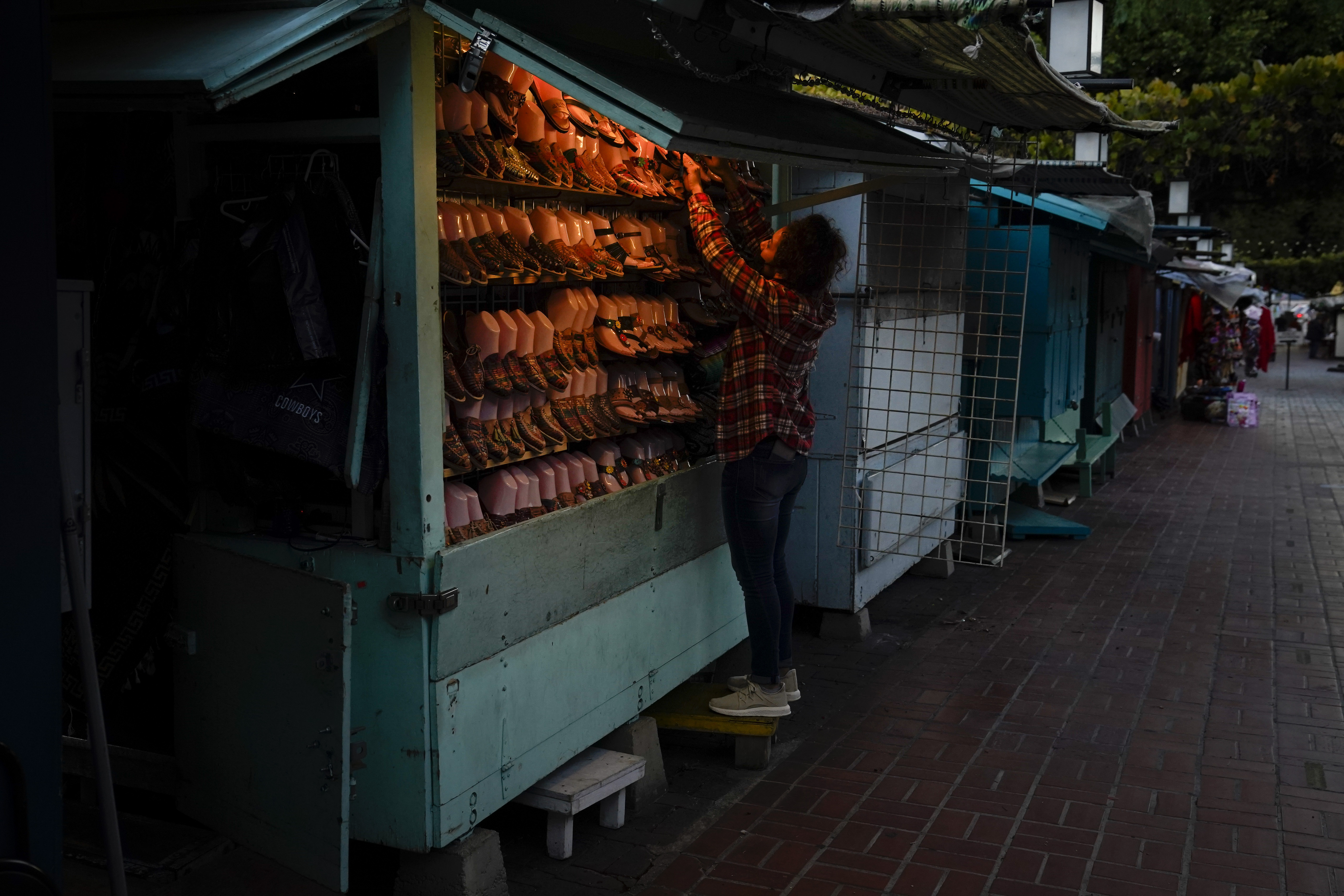 A merchant closes her shop for the day on Olvera Street in downtown Los Angeles, Tuesday, Dec. 15, 2020. Olvera Street, known as the birthplace of Los Angeles, has been particularly hard hit by the coronavirus pandemic, with shops and restaurants closed and others barely hanging on. Only a handful of businesses remain open on weekdays as tourism has cratered and downtown offices are closed and festive events held throughout the year have been canceled. (Jae C. Hong / Associated Press)