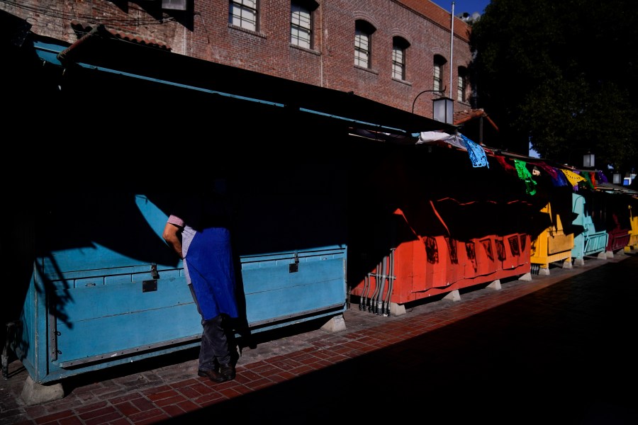 Valo Martinez, a 63-year-old cook working at El Rancho Grande, waits for customers on Olvera Street lined with shuttered market stalls in downtown Los Angeles, Wednesday, Dec. 16, 2020. Olvera Street, known as the birthplace of Los Angeles, has been particularly hard hit by the coronavirus pandemic, with shops and restaurants closed and others barely hanging on. Only a handful of businesses remain open on weekdays as tourism has cratered and downtown offices are closed and festive events held throughout the year have been canceled. (Jae C. Hong / Associated Press)