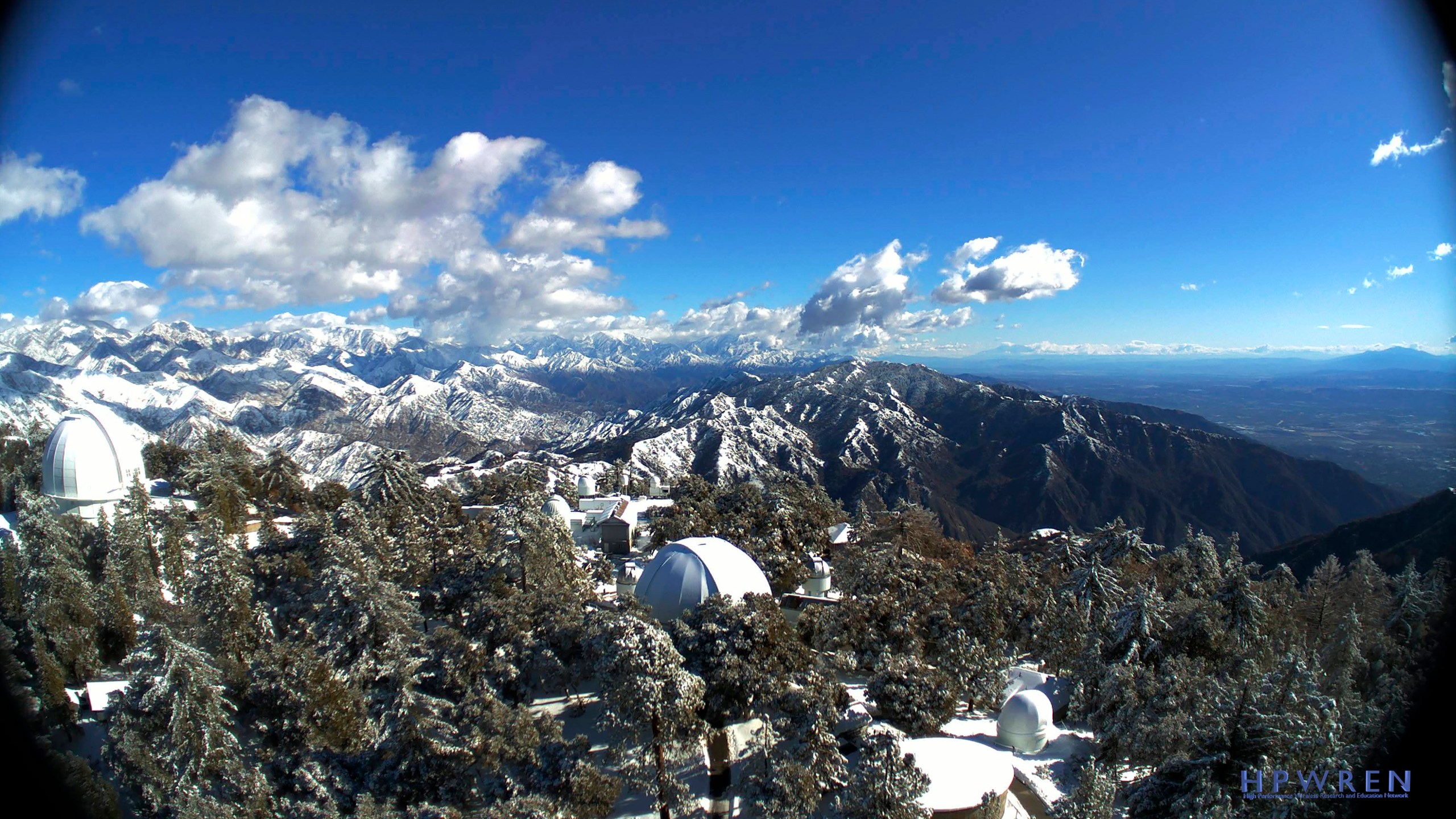 This photo provided by High Performance Wireless Research and Education Network (HPWREN) from a remote camera atop Mount Wilson shows the snow-capped San Gabriel Mountains beyond the famous observatory cluster north of Los Angeles Tuesday, Dec. 29, 2020. (HPWREN via AP)