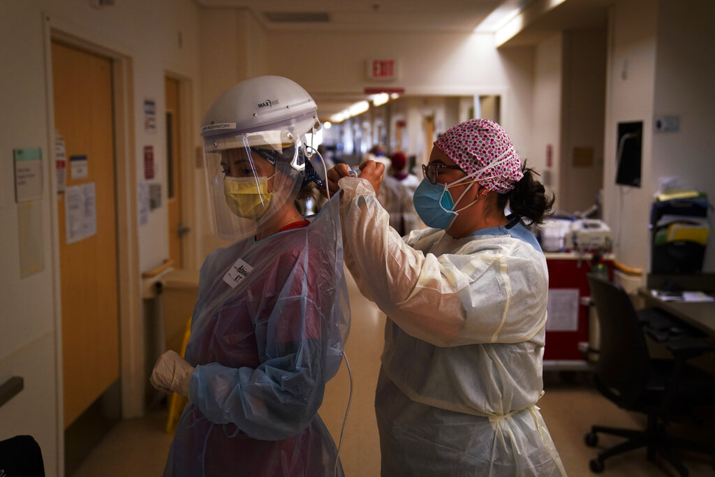 In this Dec. 22, 2020, file photo, registered nurse Dania Lima, right, helps fellow nurse Adriana Volynsky put on her personal protective equipment in a COVID-19 unit at Providence Holy Cross Medical Center in the Mission Hills section of Los Angeles. (AP Photo/Jae C. Hong, File)