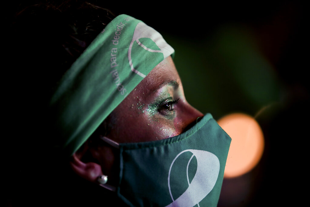 An abortion-rights activist watches live video streaming of lawmakers in session, outside Congress in Buenos Aires, Argentina, Wednesday, Dec. 30, 2020. (AP Photo/Natacha Pisarenko)