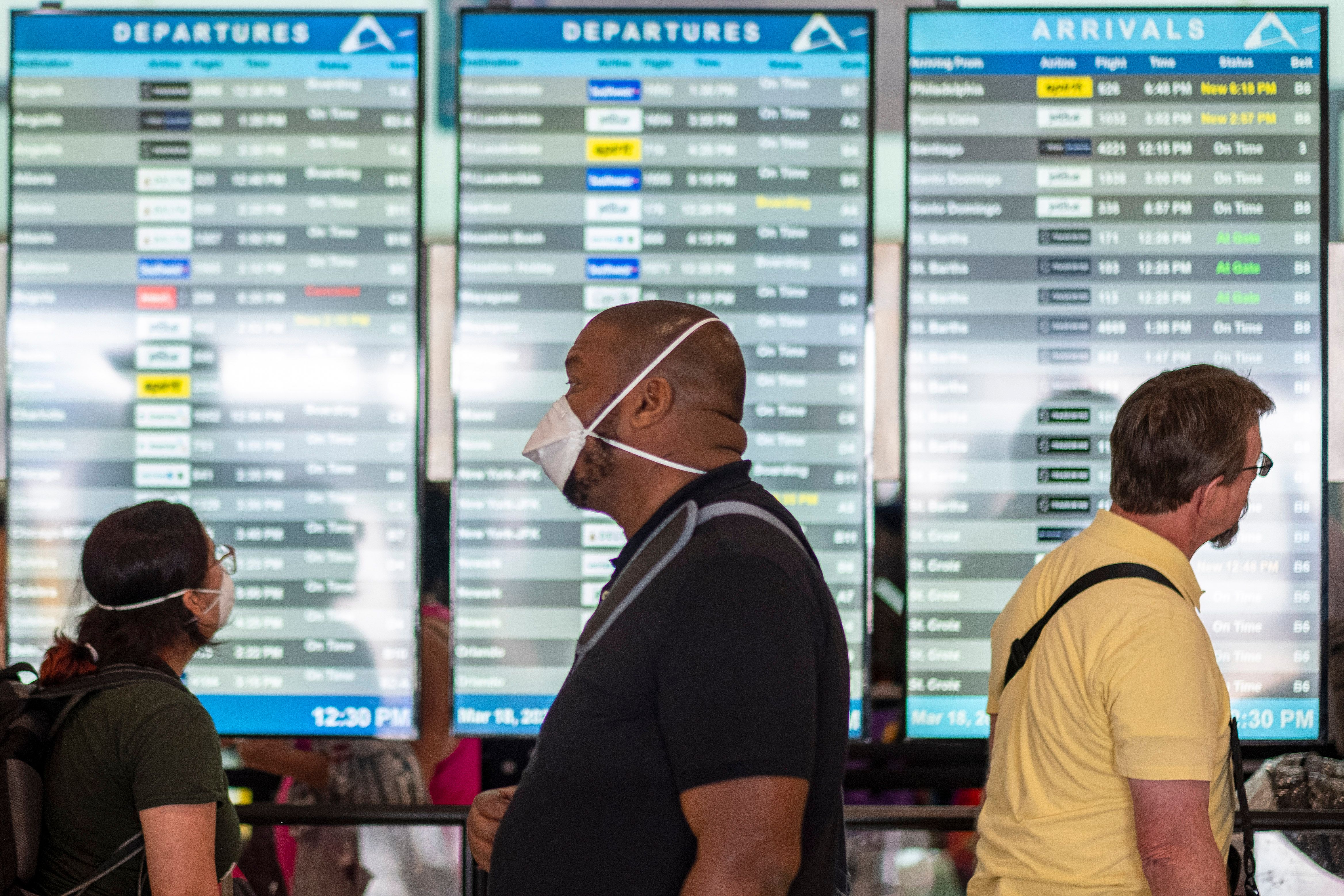 Travelers wearing masks wait in line at a security checkpoint at the Luis Munoz Marin International Airport in San Juan, Puerto Rico, on March 18, 2020. (Ricardo Arduengo / AFP / Getty Images)