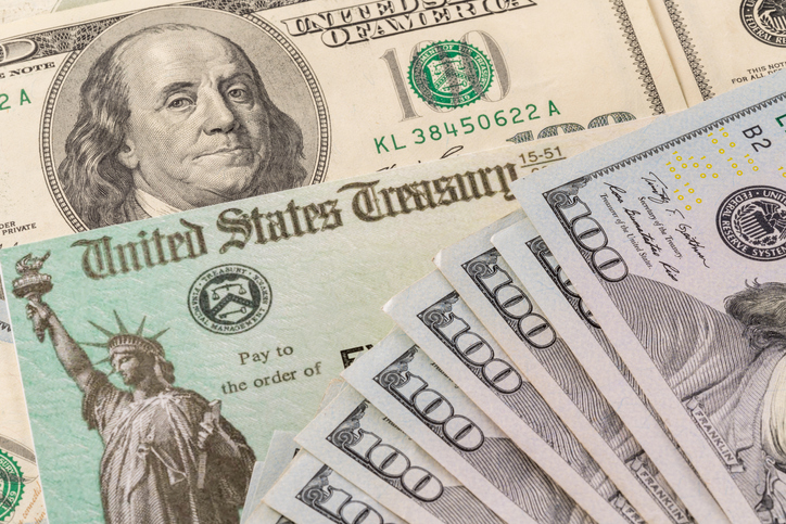 Stack of 100 dollar bills with illustrative coronavirus stimulus payment check to show the virus stimulus payment to Americans. (iStock/Getty Images Plus)