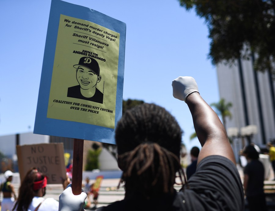 A person holds up a placard and a gloved fist during a protest in the Compton area calling for Los Angeles Sheriff's deputies to be held accountable for the shooting death of 18-year-old security guard Andres Guardado, on July 11, 2020. (ROBYN BECK/AFP via Getty Images)