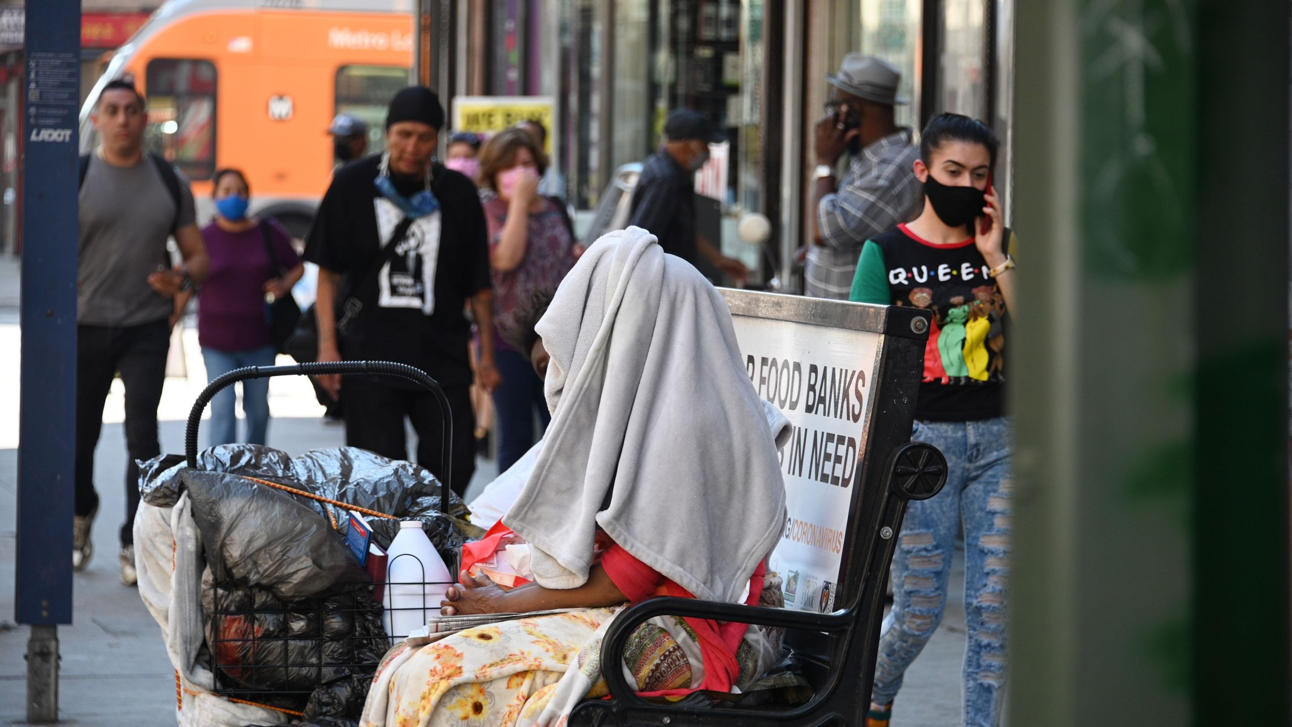 A homeless person sits on a bus bench in downtown Los Angeles on Oct. 2, 2020, amid the coronavirus COVID-19 pandemic. (Robyn Beck / AFP / Getty Images)