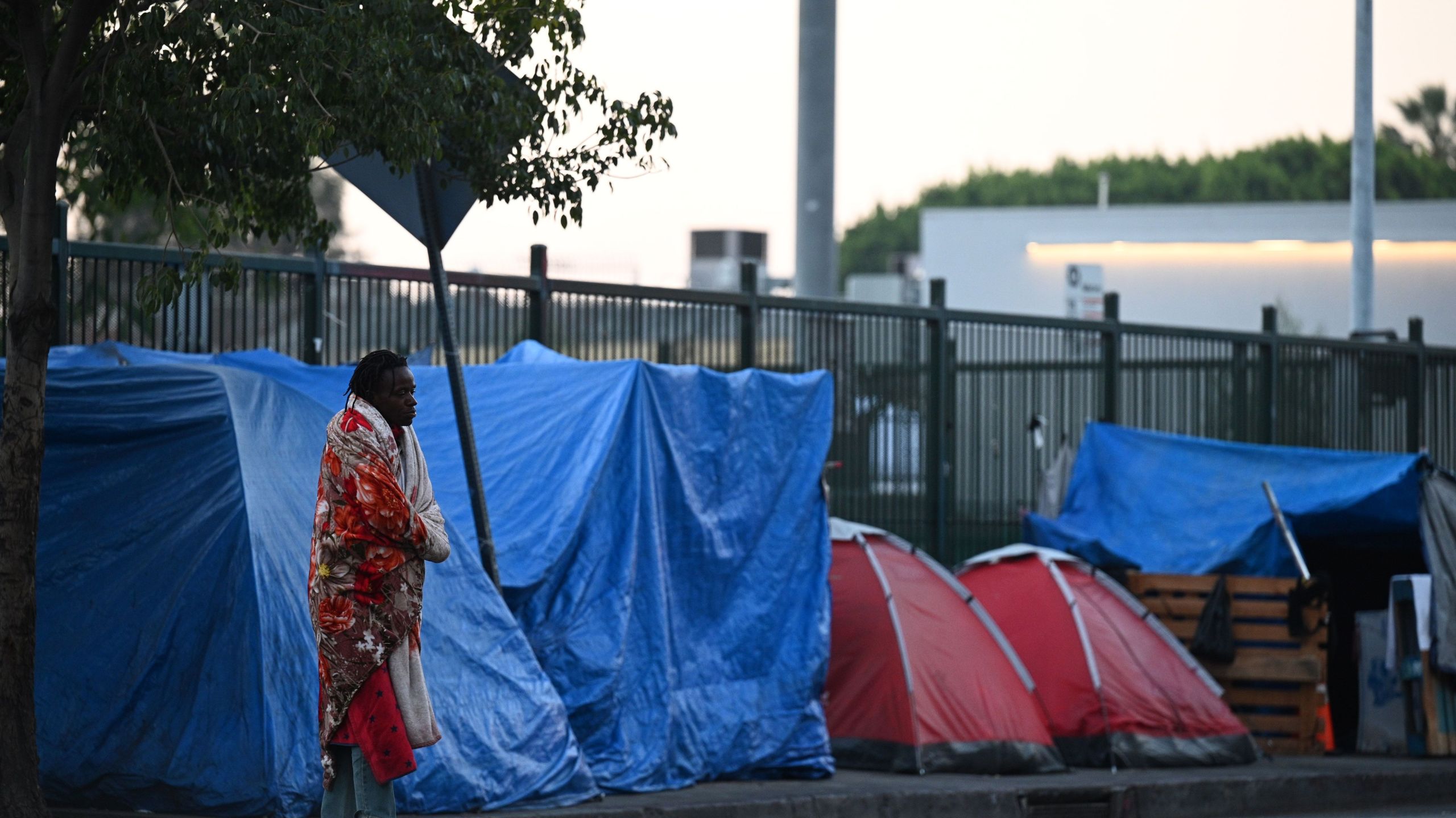 A homeless man stands outside tents on Skid Row in Los Angeles on Nov. 25, 2020, one day ahead of the Thanksgiving holiday. (Robyn Beck / AFP / Getty Images)