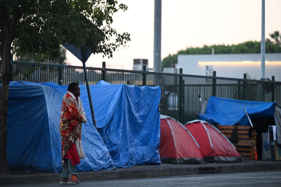 A homeless man stands outside tents on Skid Row in Los Angeles on Nov. 25, 2020, one day ahead of the Thanksgiving holiday. (Robyn Beck / AFP / Getty Images)