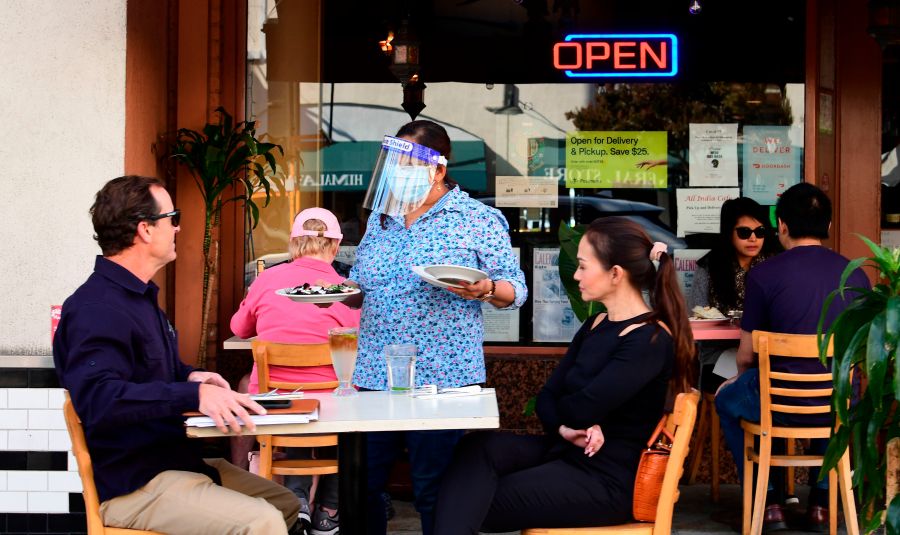 A waitress serves guests as people dine outdoors in Pasadena, the only city in Los Angeles County still allowing that service on Dec. 2, 2020. (FREDERIC J. BROWN/AFP via Getty Images)